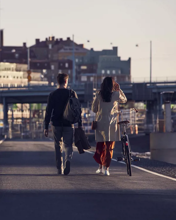 Kaksi henkilöä kävelee, toinen taluttaa pyörää