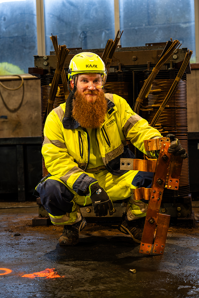 A man squating holding a piece of metal