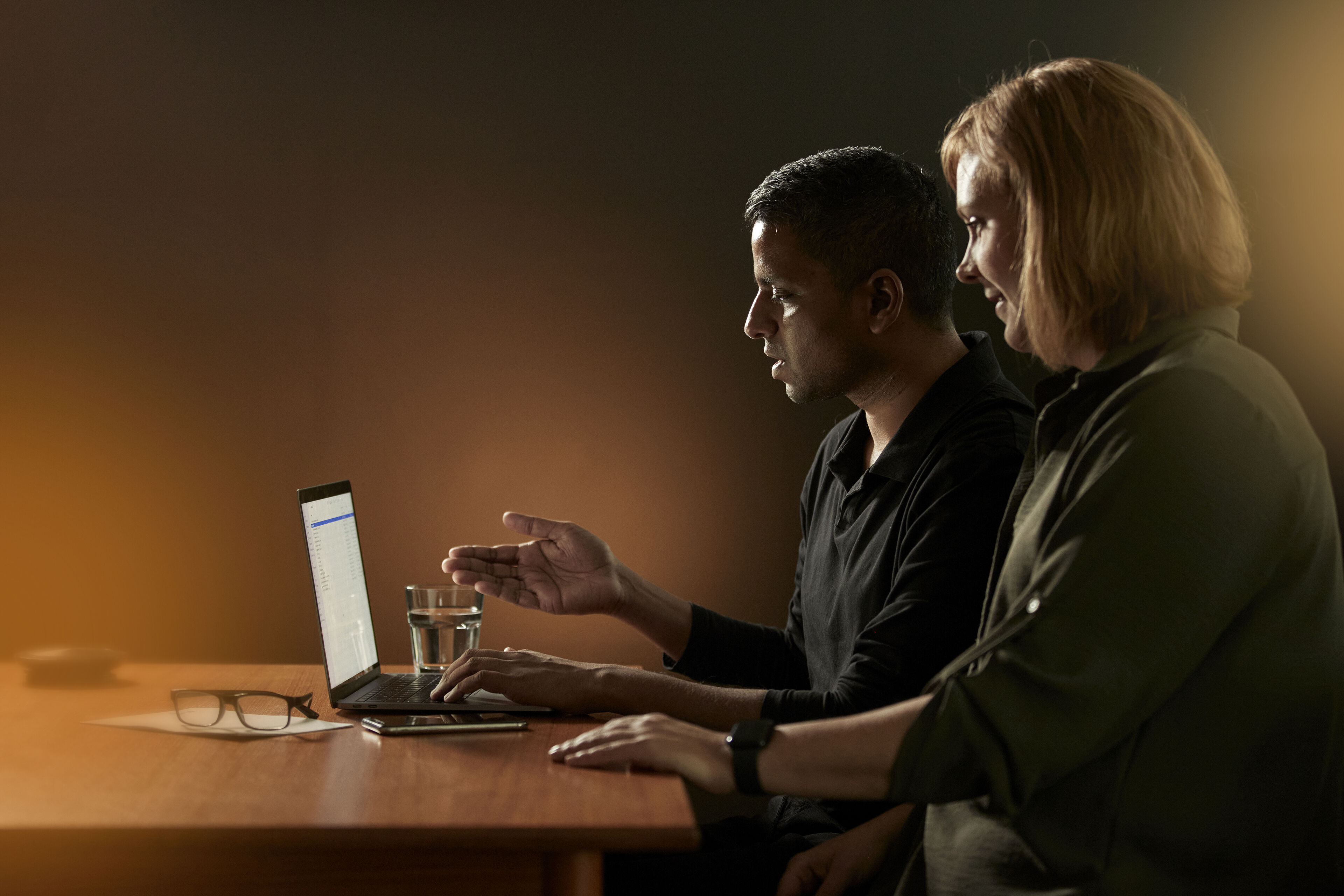 Två personer som sitter framför en laptop