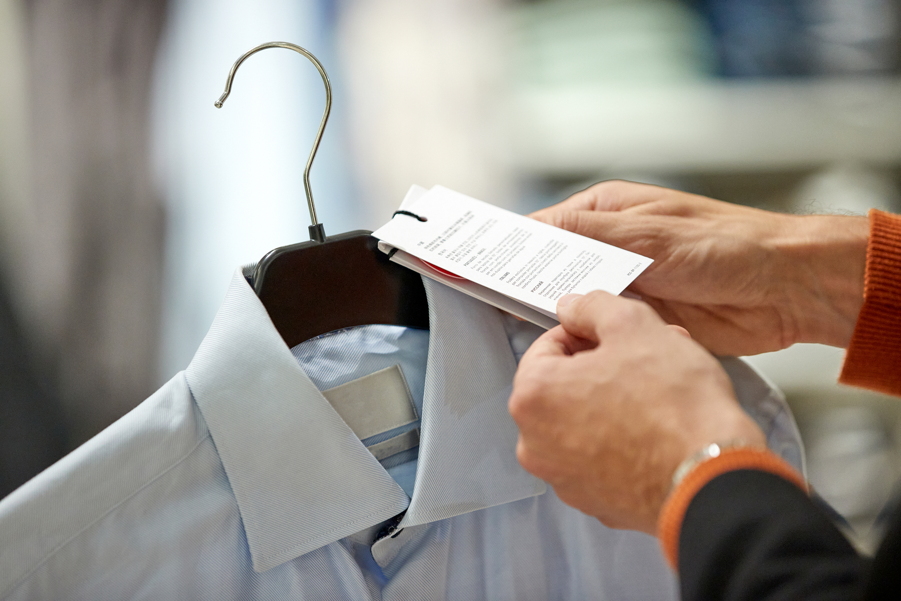 A person holding the price tag for a blue collared shirt