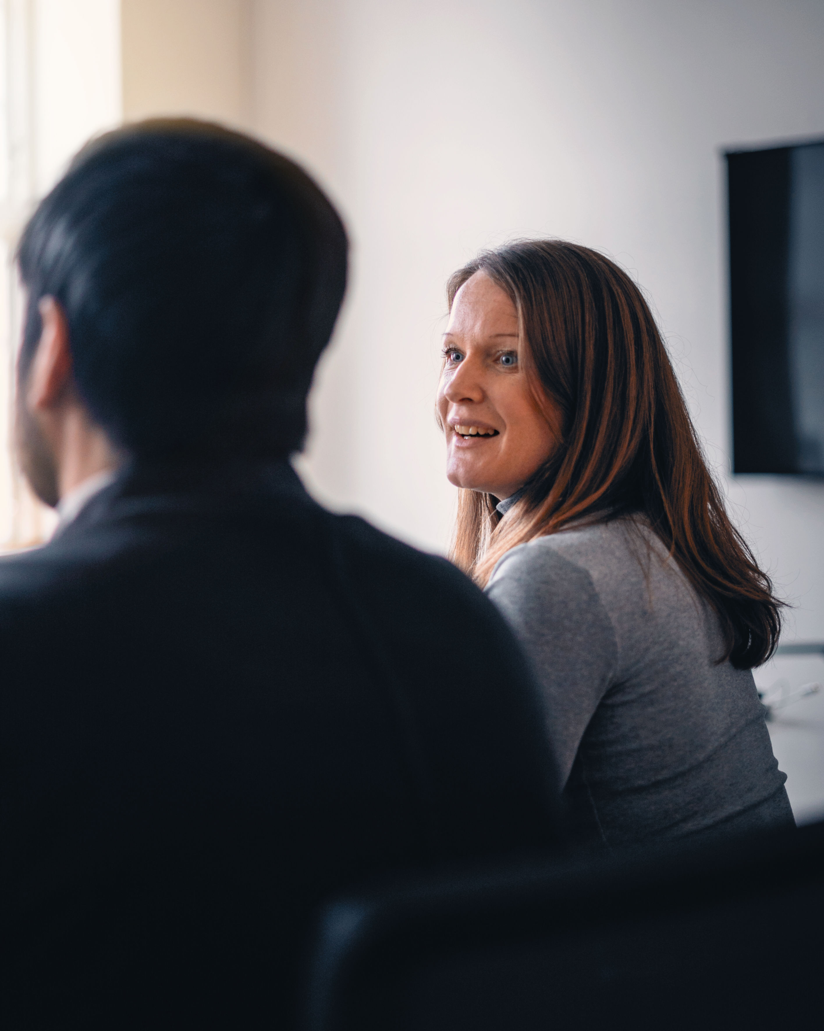 Two business people – one male and one female – sit together in a meeting room