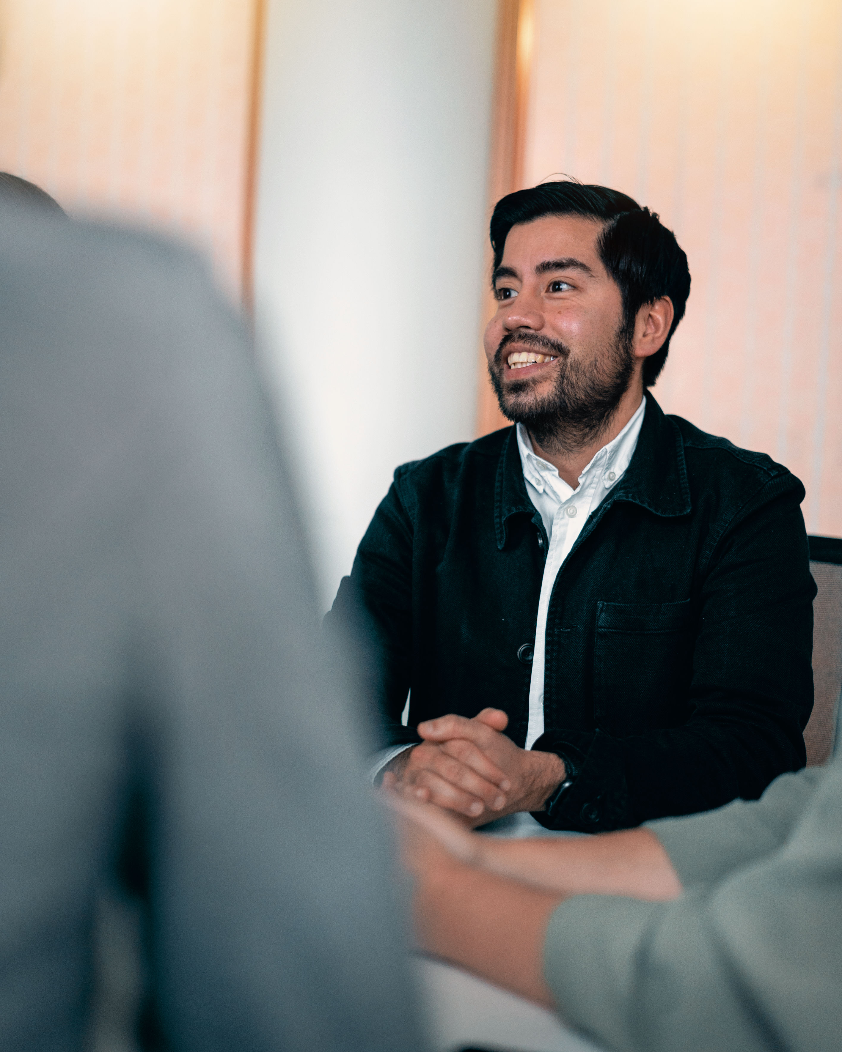 A male Stena Recycling employee smiles in a meeting room with his hands clasped