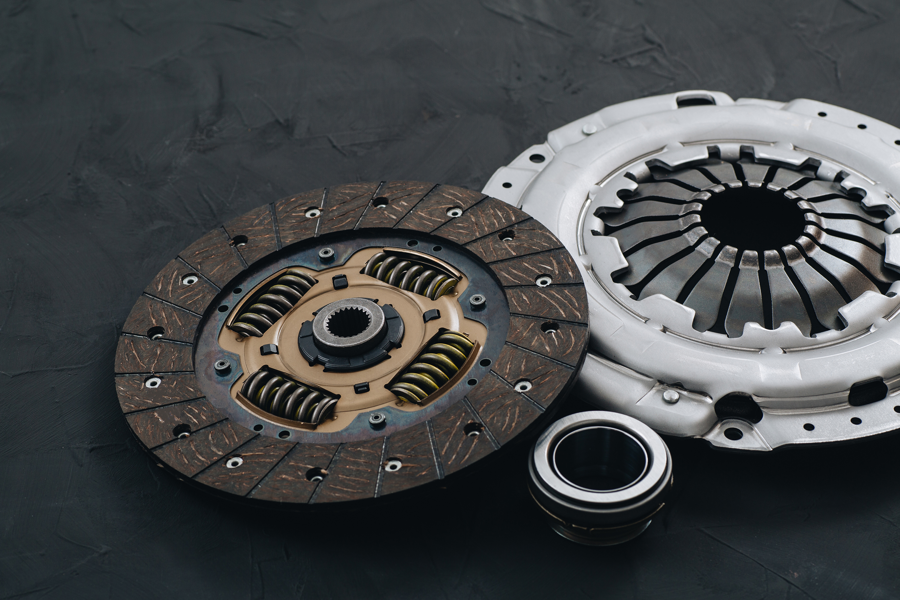 A close-up view of a clutch and clutch disc resting on a black surface.