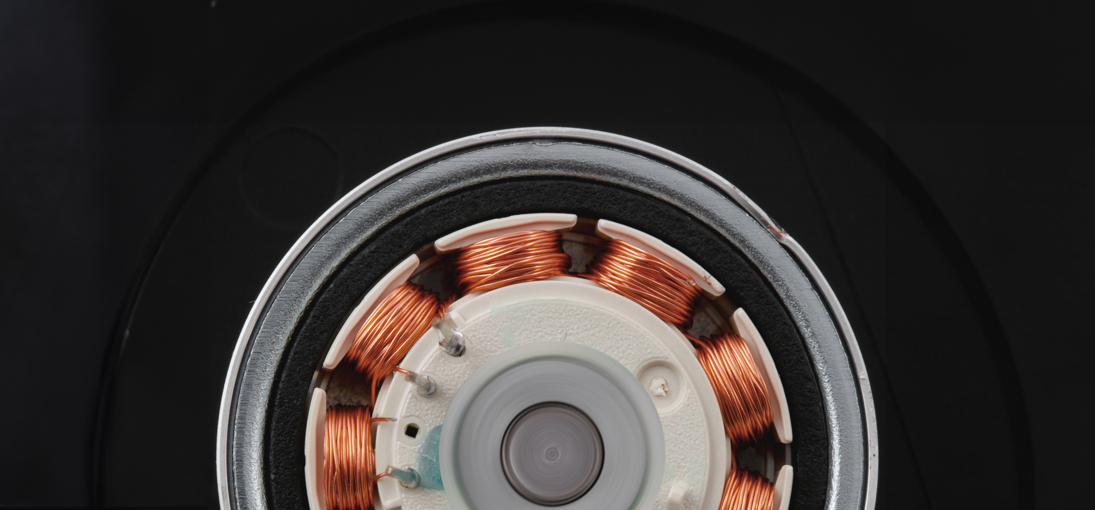 Close-up of an electric motor showing copper windings and other internal components against a black background.