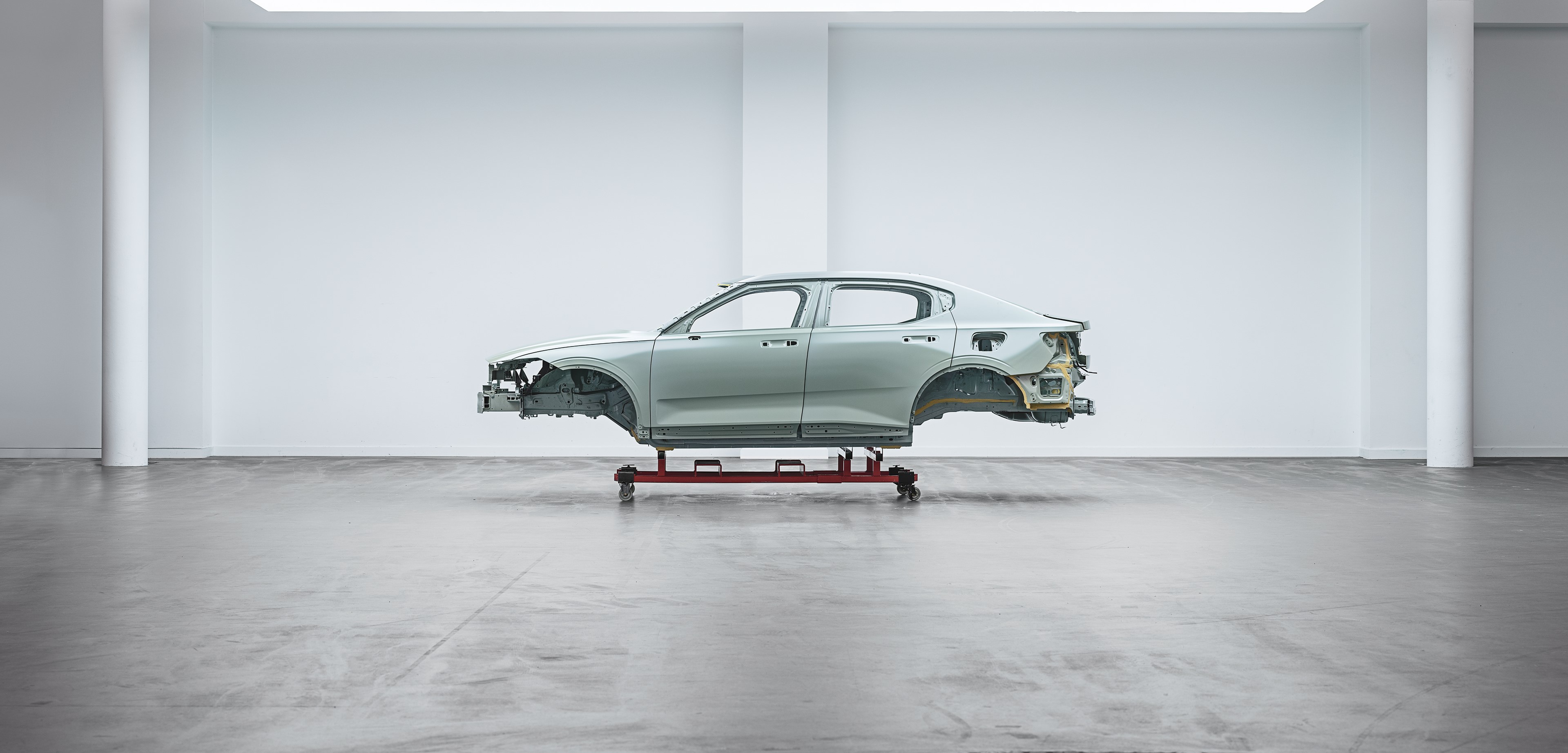 The body of a car sits raised in an empty warehouse