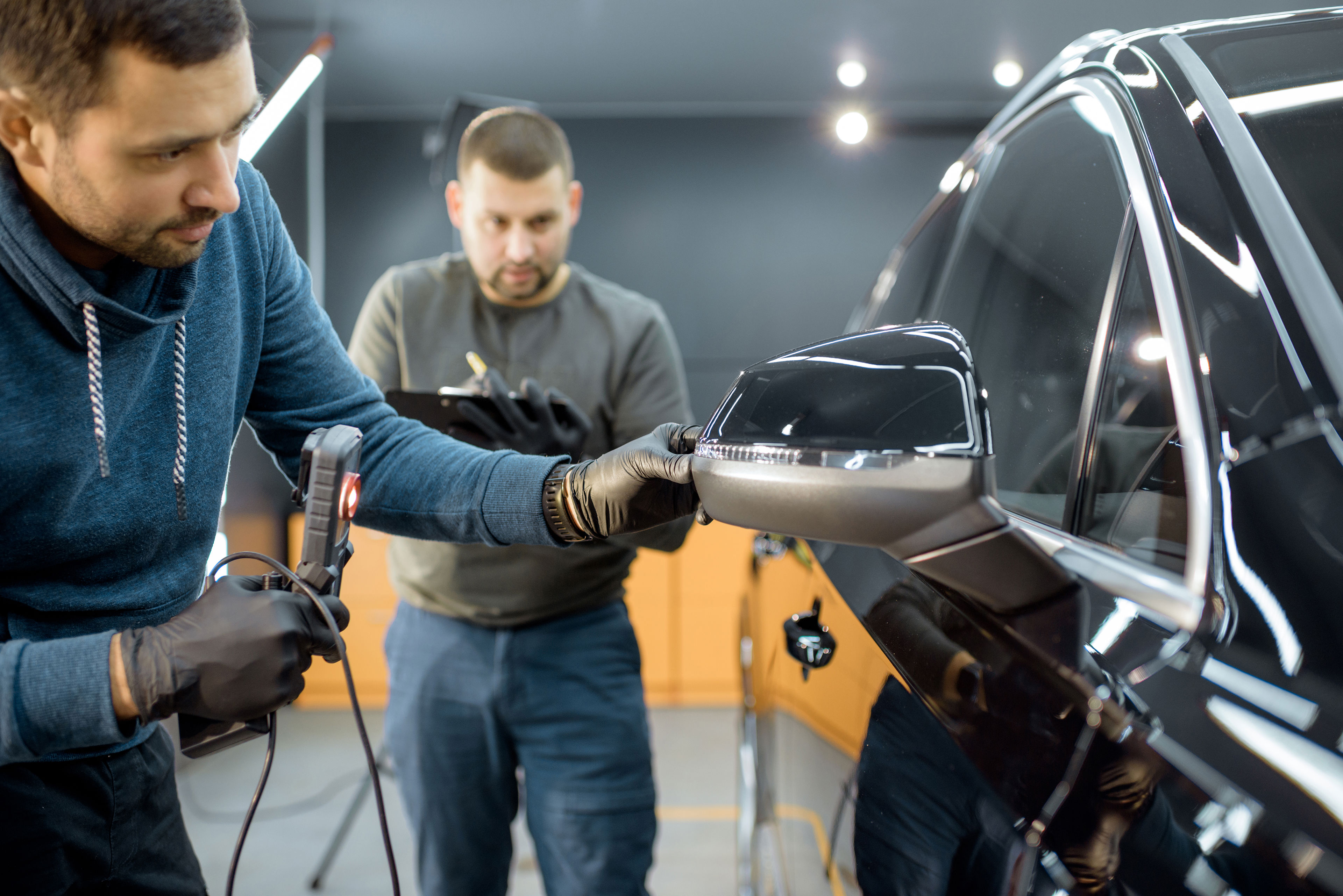 A man inspecting a car's side mirror