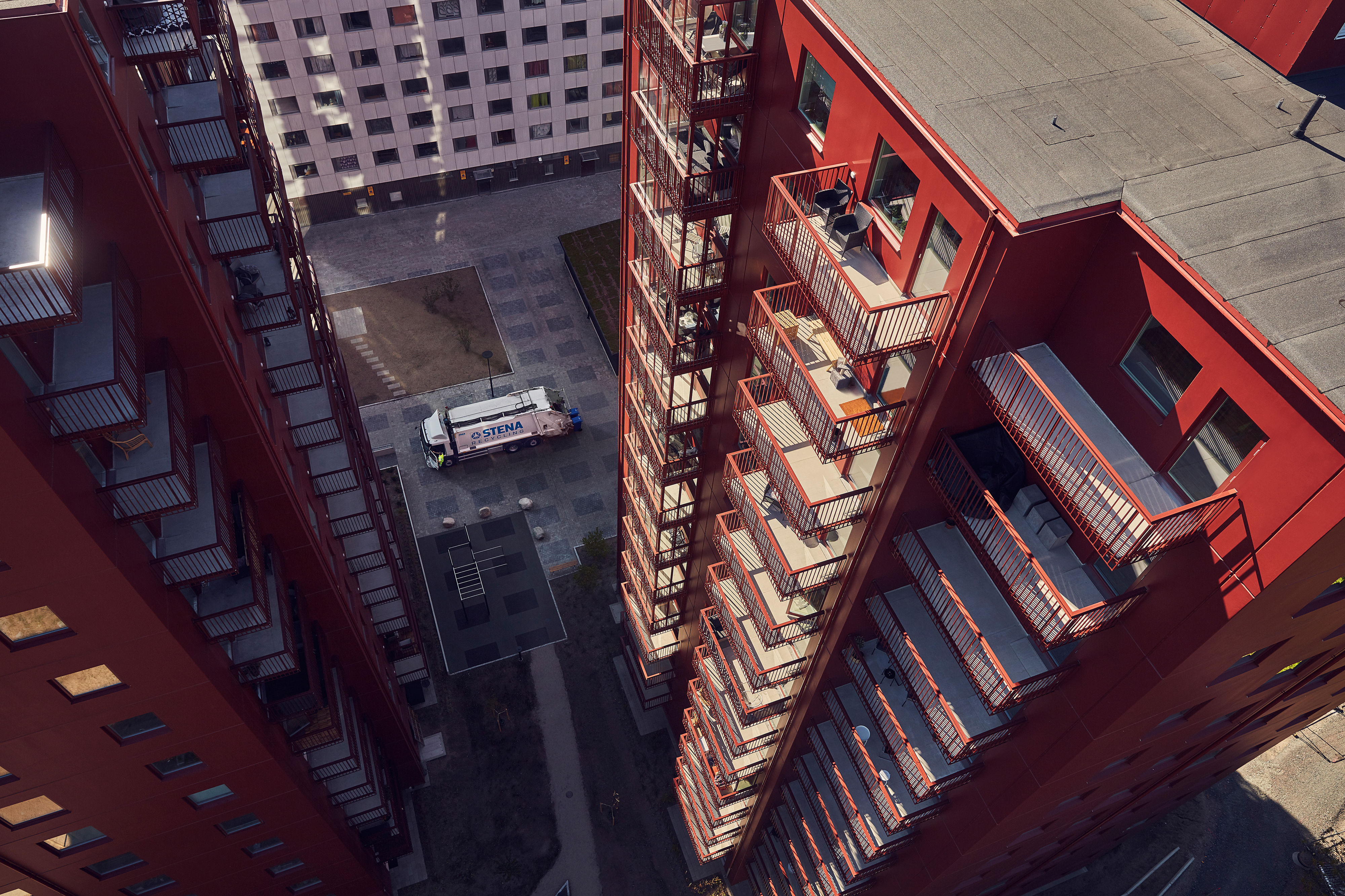 Bird’s eye view of a white Stena Recycling lorry collecting waste in a courtyard between tall residential buildings